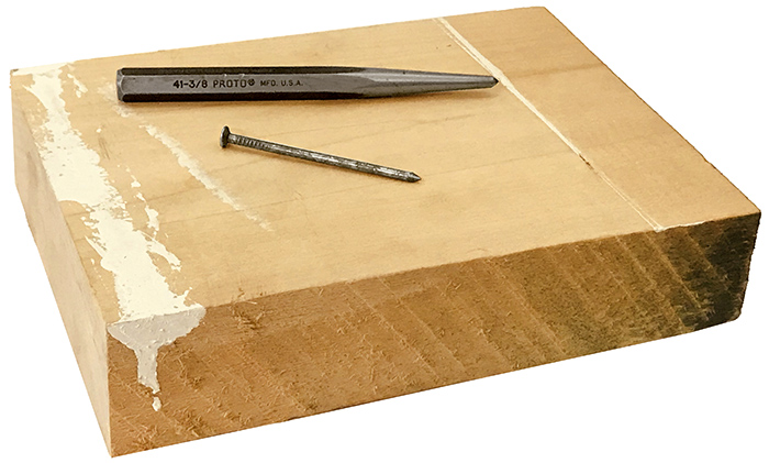 A simple and inexpensive hammer does the job. A block of wood will allow a nail or punch to easily penetrate a metal sheet. It will also protect the table surface. center-punch-nail-wood-block